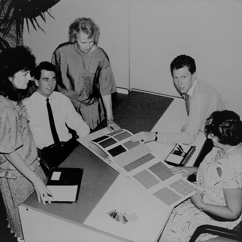 Photo of Offiscape predecessors, analysing fabric samples over a desk.  Our history